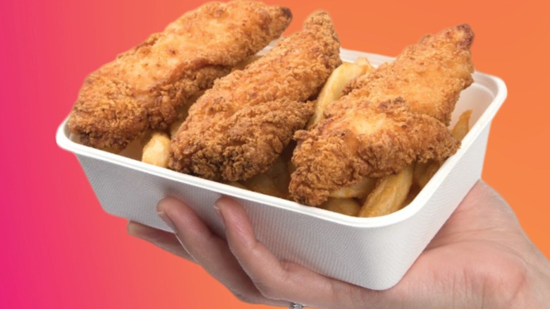 A hand holding a basket of Costco chicken strips