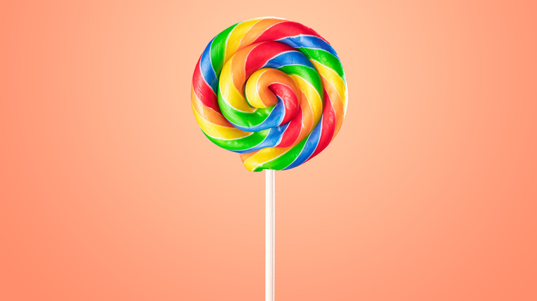 Rainbow lollipop isolated against a peach colored background