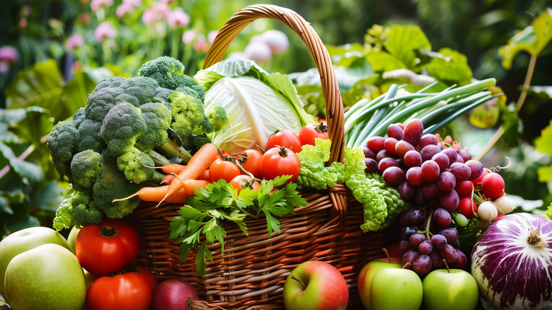Various fresh fruits and vegetables arranged together inside of and around a wicker basket