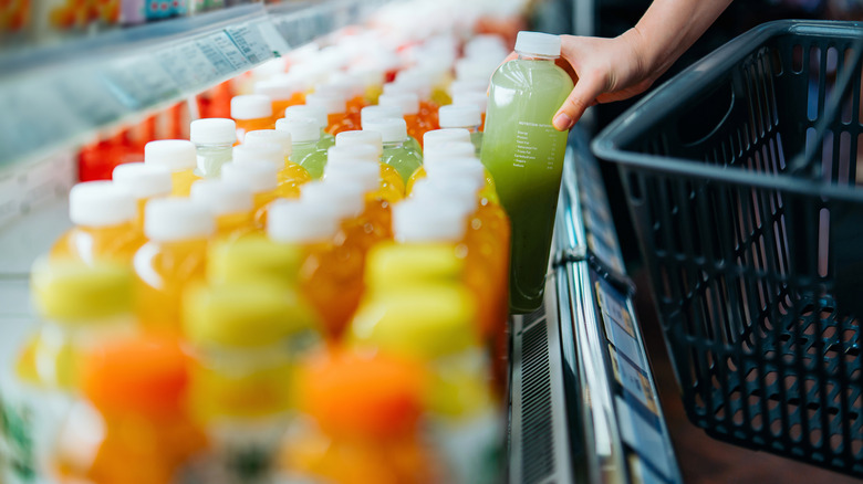 Many bottles of juice and other beverages lined up in a grocery store