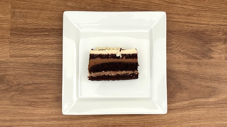 Square white plate with a slice of Costco Mocha Crunch Bar Cake on it