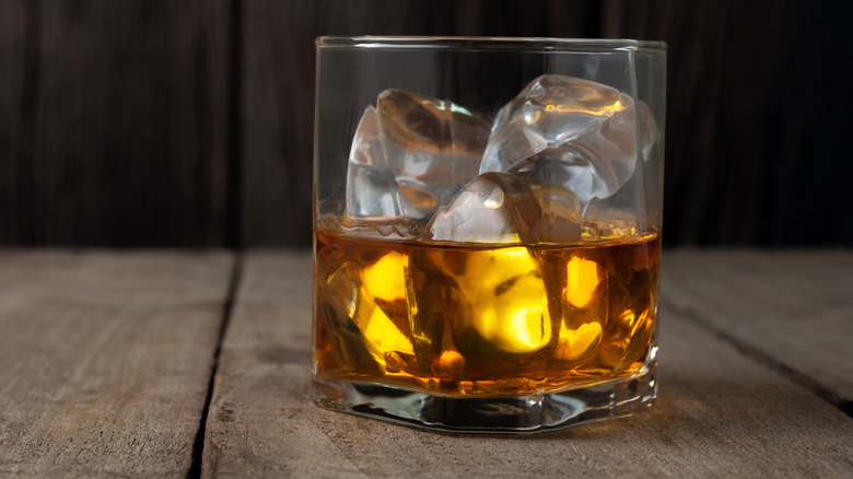 Glass of scotch whisky on the rocks on a wooden table