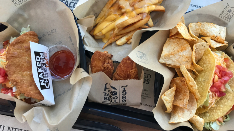 Top down view of a Taco Bell meal that includes a "Naked Chicken Taco," fries, tortilla chips, and more.