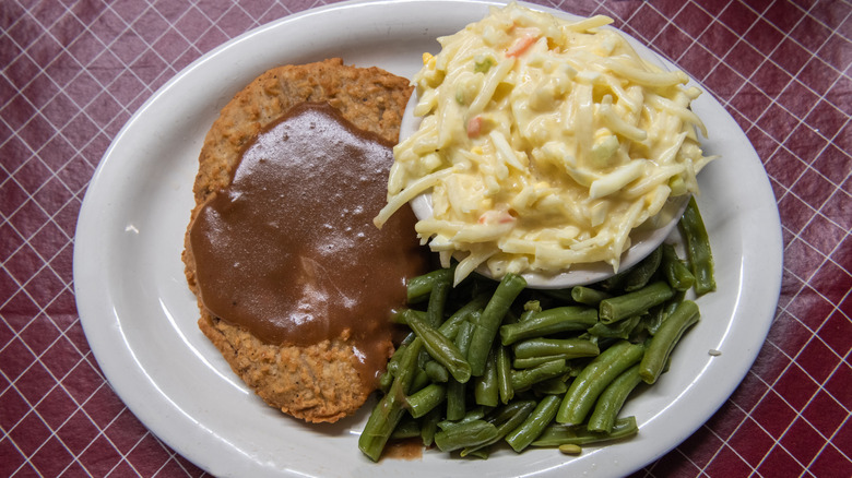 Close-up of country fried steak with pasta salad and green beans