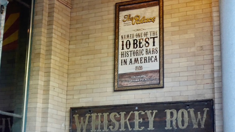 Two signs outside of the Palace, one naming it one of the best historic bars and the other labeled "whiskey row"