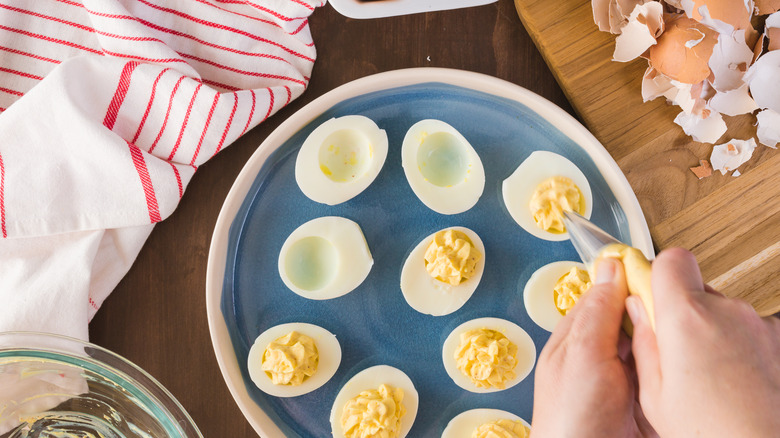 person piping egg yolk into egg whites
