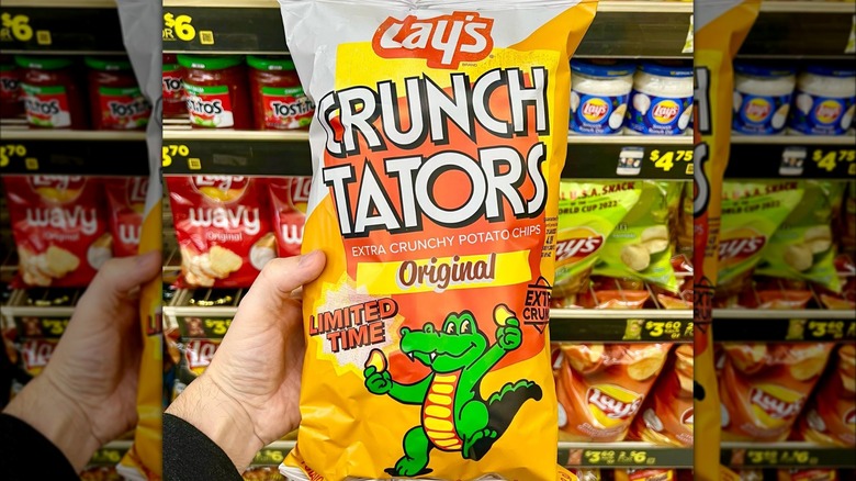 A person holds a bag of Crunch Tators chips