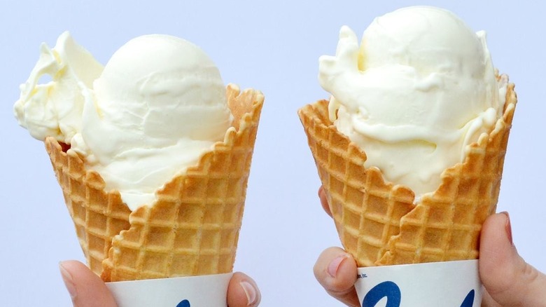 two hands holding vanilla custard cones