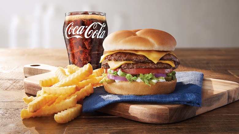 Culver's Double Deluxe with crinkle cut fries and a drink on a rustic cutting board