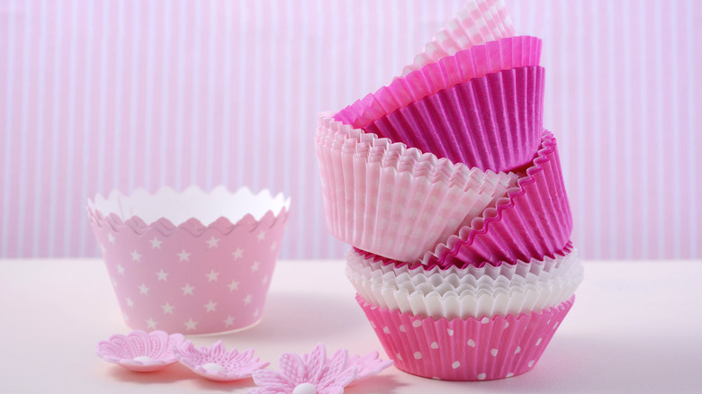 Stacks of pink cupcake liners with pink flowers in front of a striped pink background.