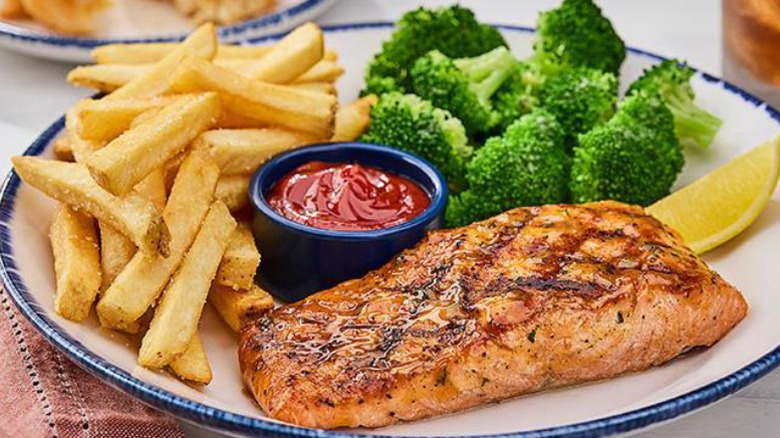a plate of Red Lobster Atlantic salmon with sides of fries, broccoli, ketchup, and lemon