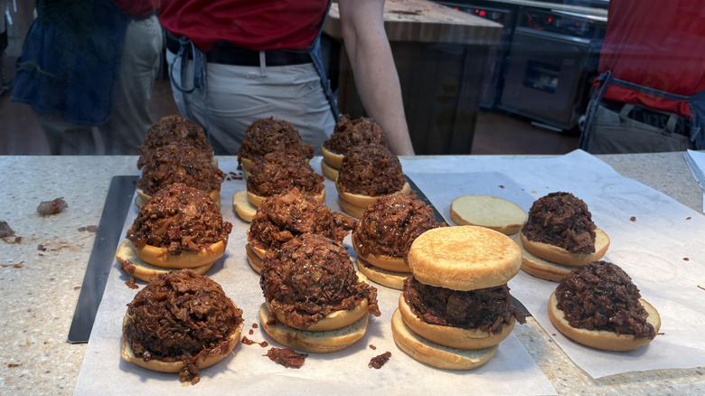 A Buc-ee's employee preparing brisket sandwiches on a white countertop