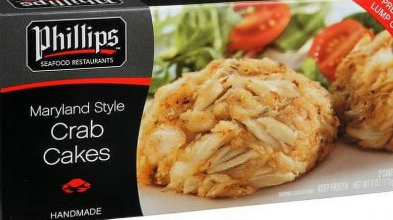 A box of Phillips Maryland Style crab cakes with photography of a crab cakes with lettuce and tomato in the background