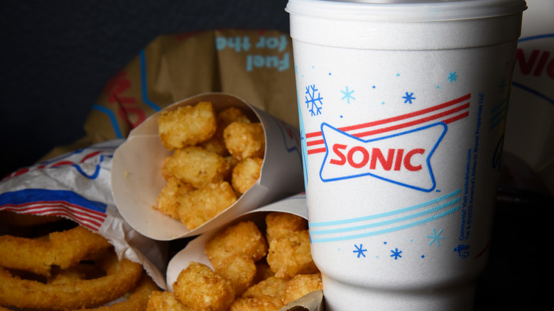 Soda, onion rings, and tater tots alongside Sonic drink