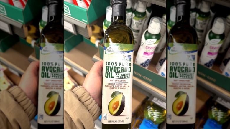 A hand holding bottle of Aldi avocado oil in the store