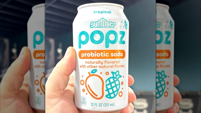 A hand holding a tropical flavor Summit Popz prebiotic soda