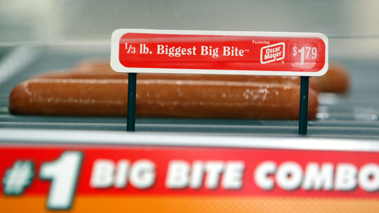 close up of hot dogs on a roller grill with a sign reading 1/3 lb Biggest Big Bite $1.79