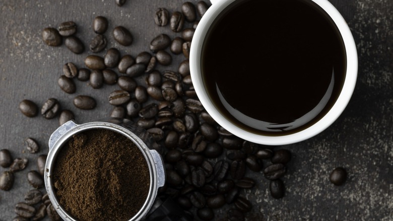 Top-down view of a mug of coffee next to ground espresso beans