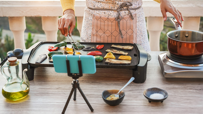person in apron watching virtual cooking tutorial