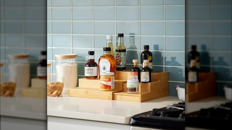 Three tiered expandable shelf on kitchen counter with jars and bottles on it