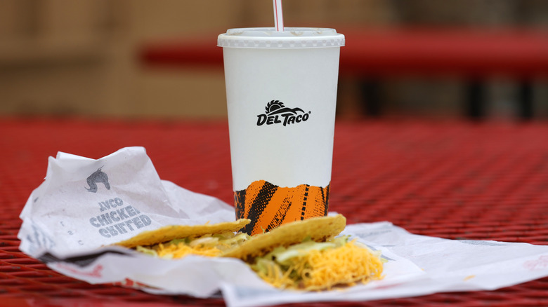 Del Taco cup with tacos on a red picnic table