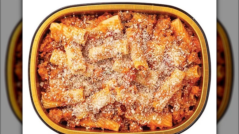 A golden container filled with rigatoni, tomato sauce, and cheese on top