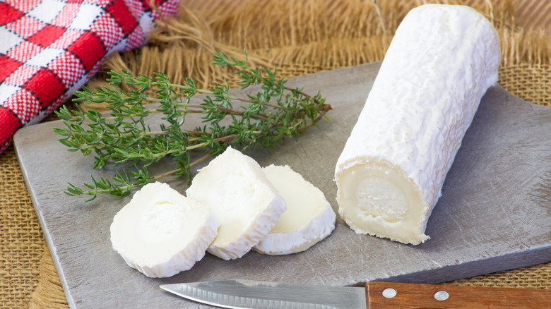 sliced goat cheese and thyme on cutting board