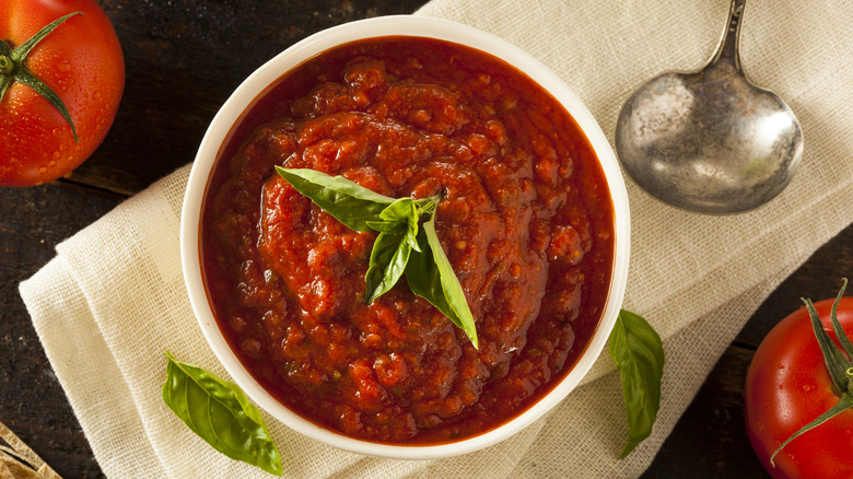 Marinara sauce in a white bowl with basil garnish