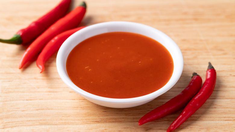 Sriracha sauce in a bowl, with red chiles