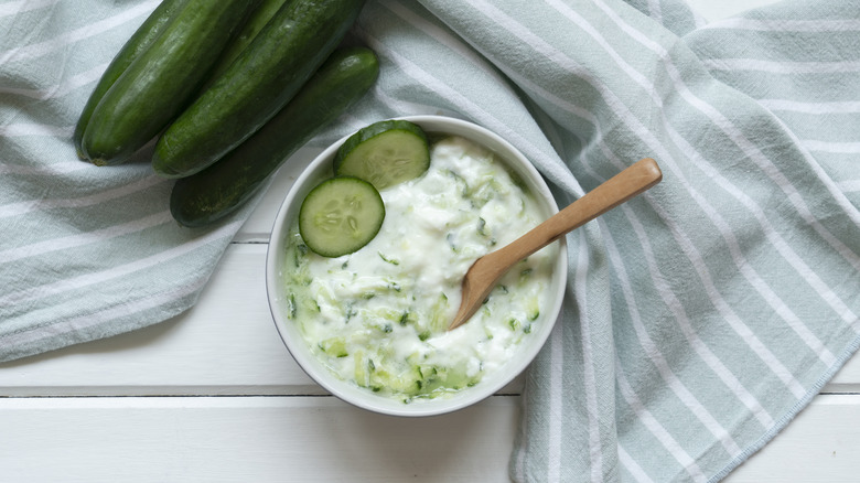 Tzatziki in a bowl with fresh cucumbers