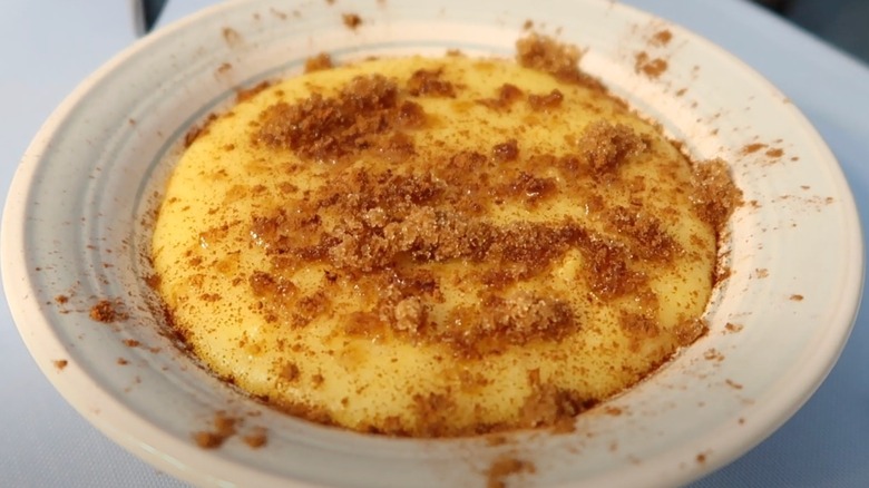 A bowl of cornmeal pudding, with brown sugar sprinkled on top