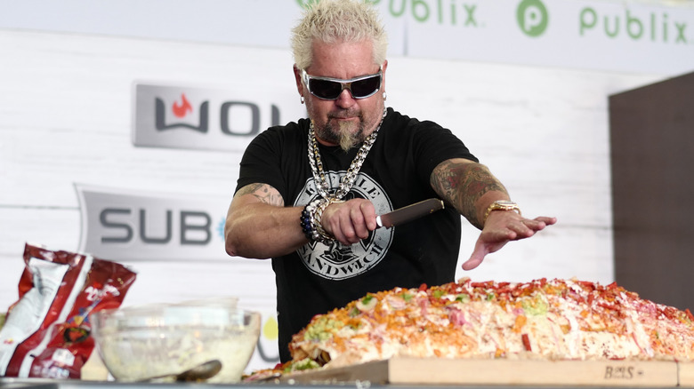 Guy Fieri standing before a giant burrito