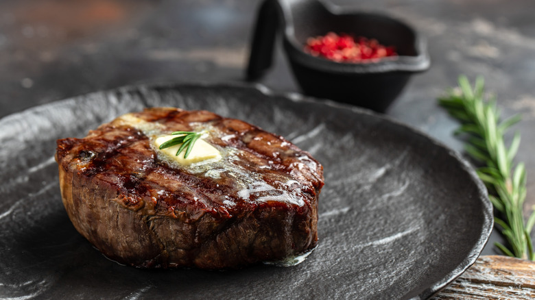A grilled beef tenderloin steak topped with melted butter