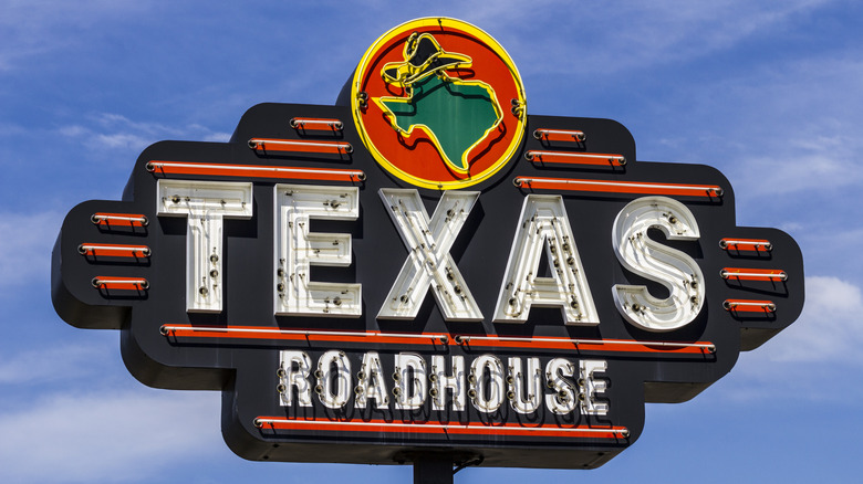 A Texas Roadhouse neon sign against a blue sky