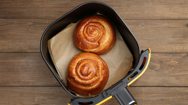 An air fryer basket with two cinnamon rolls
