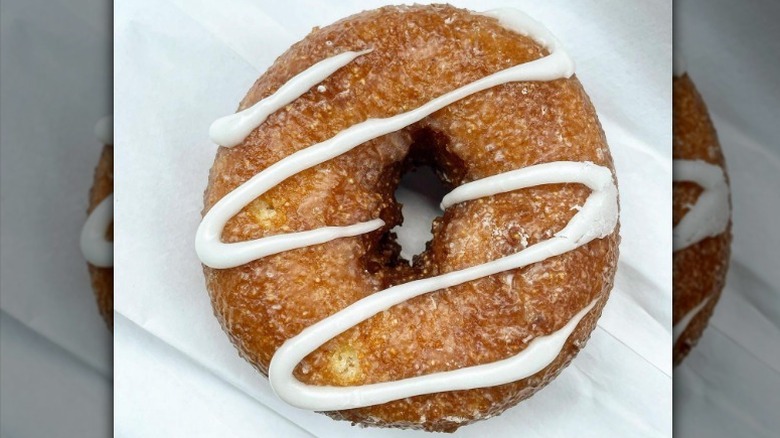 Cornbread donut with a grainy looking texture and a drizzle of white icing