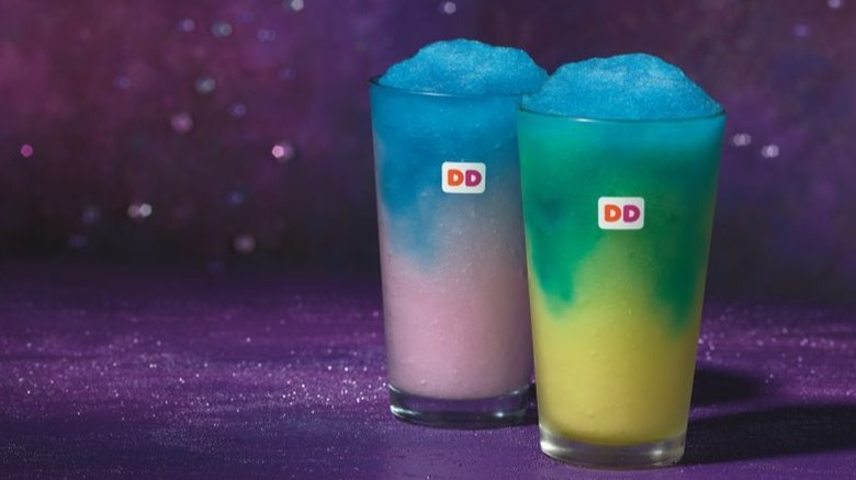 Two vibrantly colored Dunkin' slushies, in shades of sky blue, lime green, and light purple