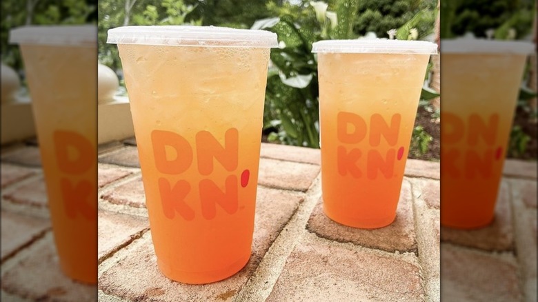 Two Dunkin' Peach Passion Fruit Refreshers on outdoor brick