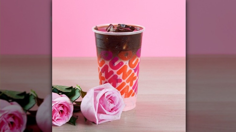 Pink and brown Dunkin' coffee drink in a plastic cup, with pink roses