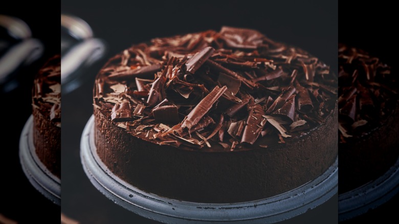 A chocolate cake with chocolate shavings on top on a pedestal
