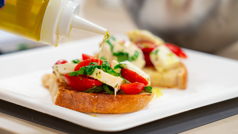 drizzling oil onto open-face tomato and cheese sandwich