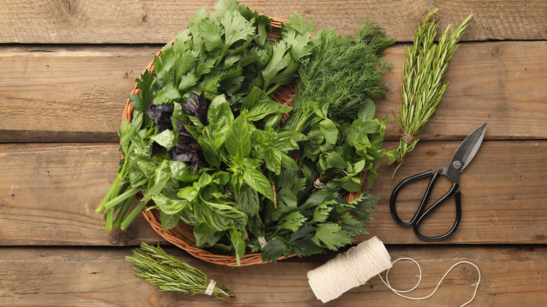 Various aromatic herbs in a basket, flat lay.