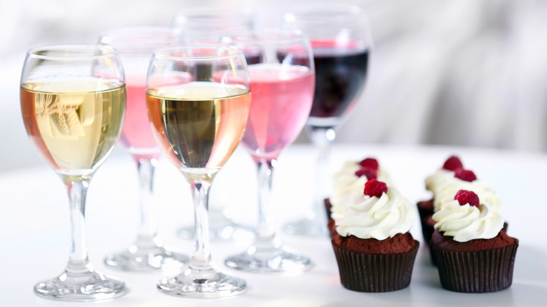 glasses of wine next to cupcakes