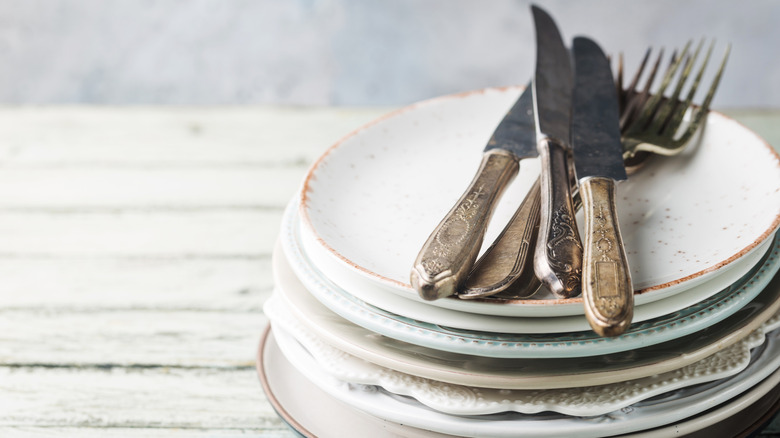 Stack of mismatched dishes and cutlery