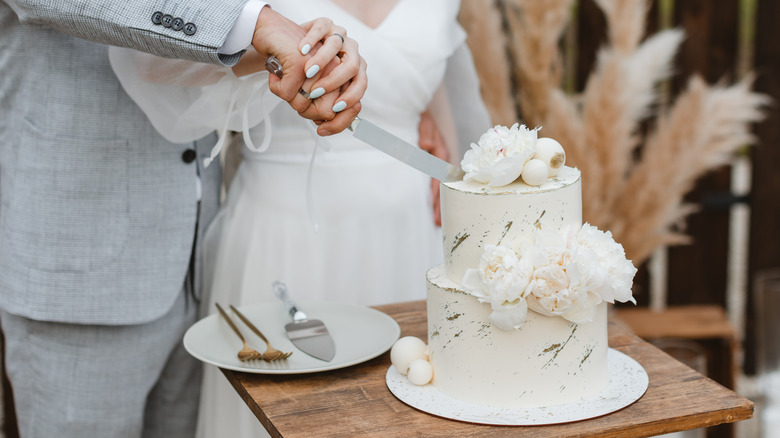 Bride and groom hands cutting wedding cake