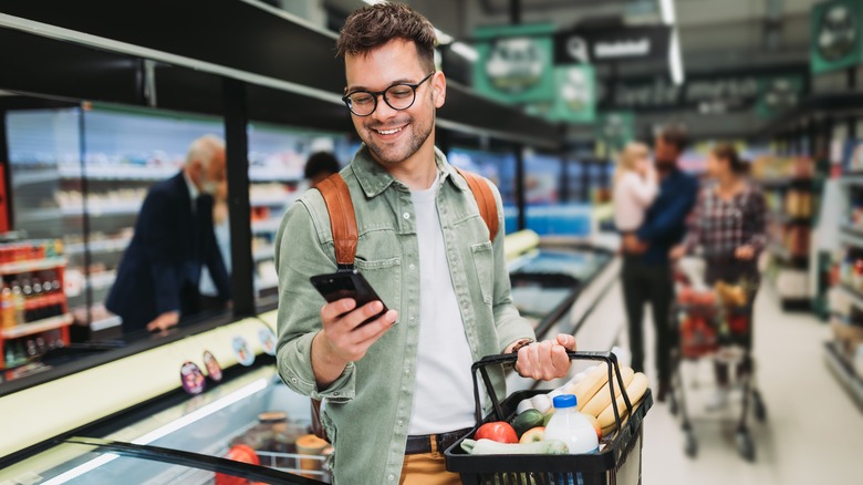 Person smiling at mobile device as they grocery shop