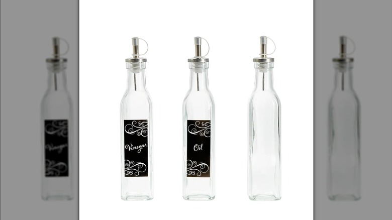 Three tall, slim glass bottles with metal spouts. One is labeled "oil," another "vinegar," and the third unlabeled.