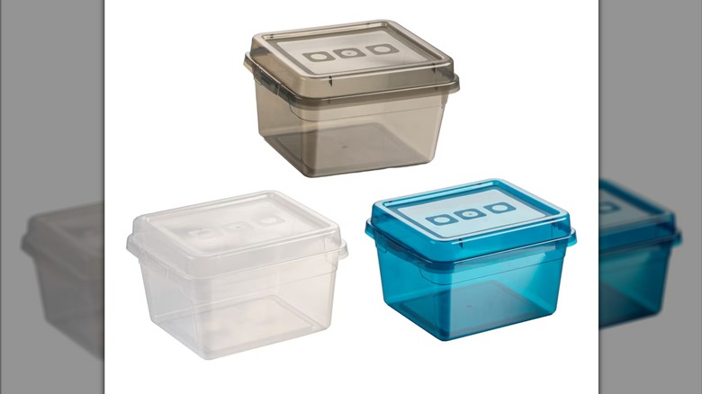 Three clear rectangular plastic storage containers with lids, in white, gray, and blue