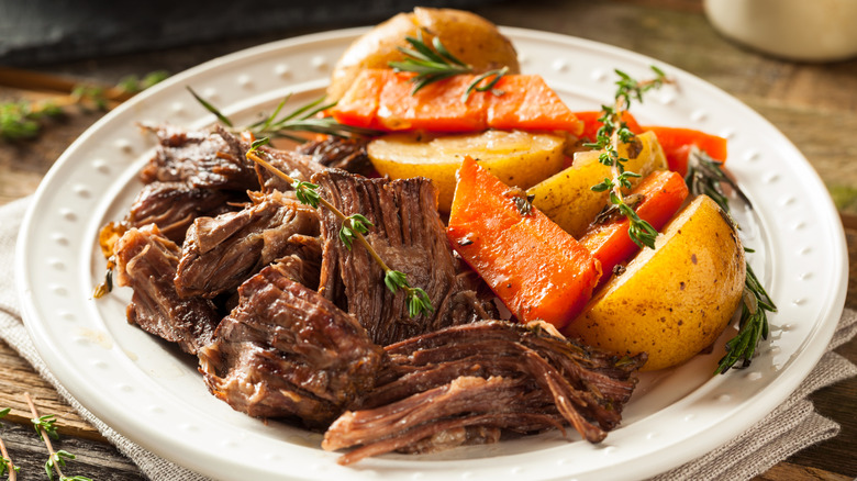 Pot roast with potato and carrot on a white plate