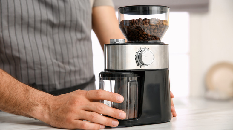 Close up of a person using a coffee grinder on the counter.